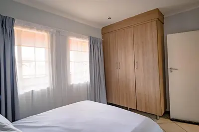 a bedroom with a bed and a wooden cabinet at Entire Modern Comfortable Lux Centurion Apartment in Pretoria