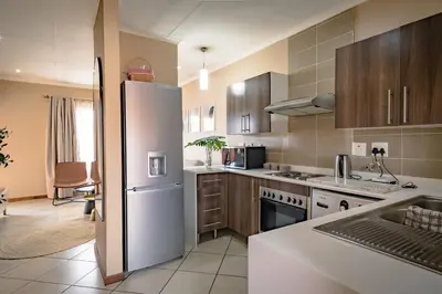 a kitchen with a white refrigerator and wooden cabinets at Entire Modern Comfortable Lux Centurion Apartment in Pretoria