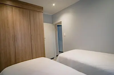 a bedroom with two beds and a wooden cabinet at Entire Modern Comfortable Lux Centurion Apartment in Pretoria