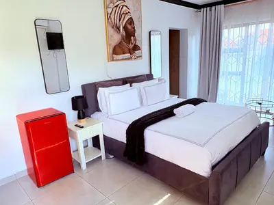 a bedroom with a large bed with a red night stand at 43 Home Reyno Ridge in Witbank