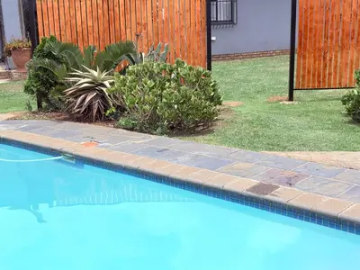 a blue swimming pool with plants in a yard at 43 Home Reyno Ridge in Witbank