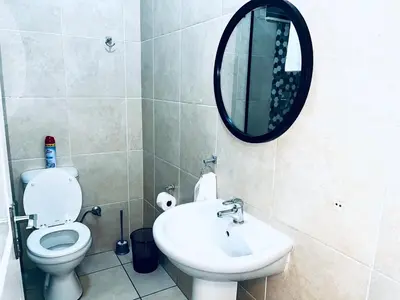 a bathroom with a toilet and a sink and a mirror at Stylish 1 Bed Self Catering Near OR Tambo in Kempton Park