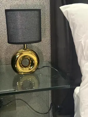 a lamp on a glass table next to a bed at 4413 At Ellipse Waterfall in Midrand