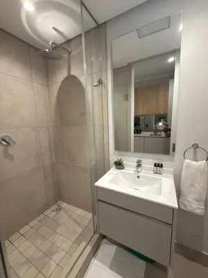 a bathroom with a sink and a shower with a mirror at 4413 At Ellipse Waterfall in Midrand