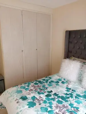 a bedroom with a bed with a floral bedspread at Fairway Gardens in Pretoria