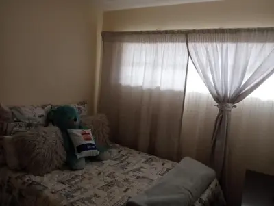 a teddy bear sitting on a bed in a bedroom at Fairway Gardens in Pretoria