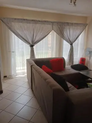 a living room with a couch in front of a window at Fairway Gardens in Pretoria