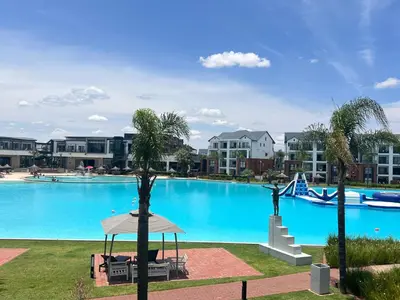 a large blue swimming pool with palm trees in a resort at The Blyde 1 bed Tribe in Pretoria