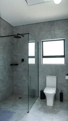 a bathroom with a toilet and a glass shower at Mupauli Boutique Lodge