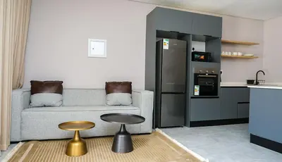 a living room with a couch and a table and a kitchen at Mupauli Boutique Lodge