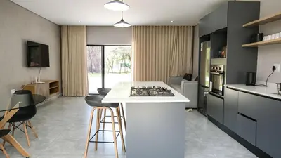 a kitchen with a white counter and some stools at Mupauli Boutique Lodge