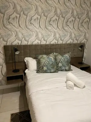 a bedroom with a bed with a patterned wall at Unit 438, The Blyde, Pretoria East in Pretoria
