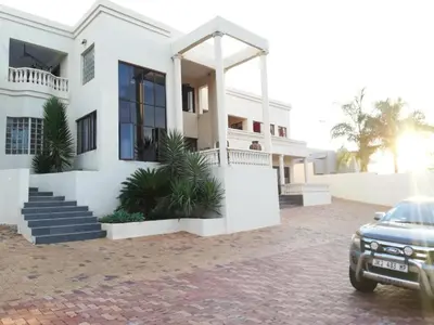 a white house with a car parked in front of it at Casadeross Guest House in Pretoria