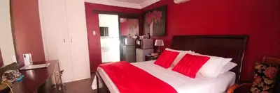 a red bedroom with a large bed with red pillows at Casadeross Guest House in Pretoria