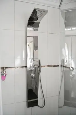 a white bathroom with a shower and a mirror at Casadeross Guest House in Pretoria