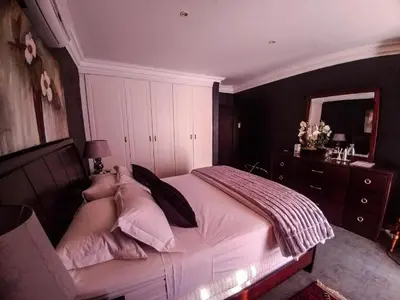 a bedroom with a large bed with pink pillows at Casadeross Guest House in Pretoria