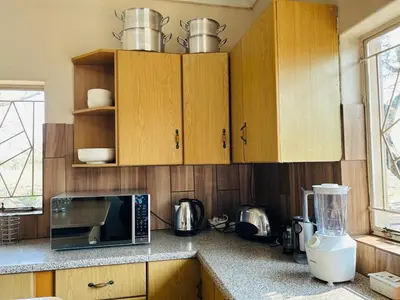 a kitchen with wooden cabinets and a microwave oven at Bird & Bed Farmhouse in Brits