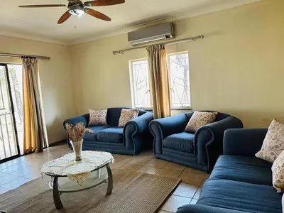 a living room with blue couches and a table at Bird & Bed Farmhouse in Brits
