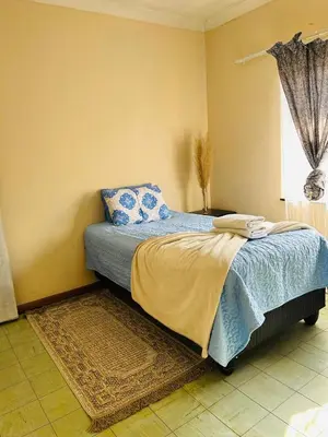 a bedroom with a bed with blue sheets and a window at Bird & Bed Farmhouse in Brits