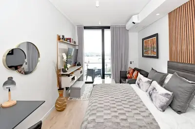 a bedroom with a large bed and a mirror at Stylish Penthouse Studio in Ellipse Waterfall in Midrand