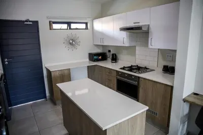 a kitchen with white cabinets and a white counter top at Maude Retreats in Midrand