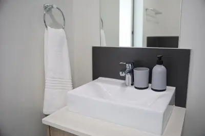 a bathroom sink with two bottles of soap and a mirror at Maude Retreats in Midrand
