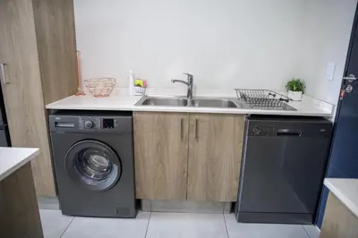 a kitchen with a sink and a washing machine at Maude Retreats in Midrand
