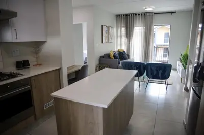 a kitchen and living room with a white counter top at Maude Retreats in Midrand