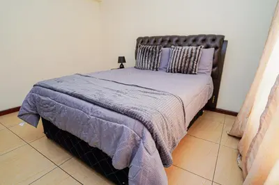 a bedroom with a bed with a purple comforter at Royal Palm in Mokopane