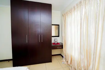 a large wooden cabinet in a bedroom with a desk at Royal Palm in Mokopane