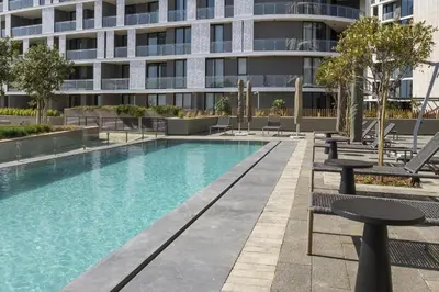a swimming pool with chairs and a building at Ellipse Waterfall 41110 in Midrand