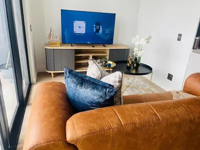 a brown couch in a living room with a television at Ellipse Waterfall 41110 in Midrand