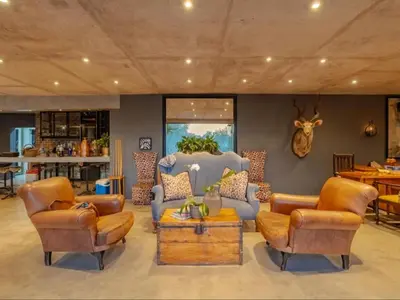 a living room with leather chairs and a table at Dombeya Private Game Reserve in Vaalwater