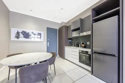 a kitchen with a table and chairs in a room at Menlyn Main Apartments Trilogy Collection in Pretoria