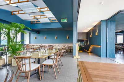 a restaurant with wooden tables and chairs and blue walls at Menlyn Main Apartments Trilogy Collection in Pretoria