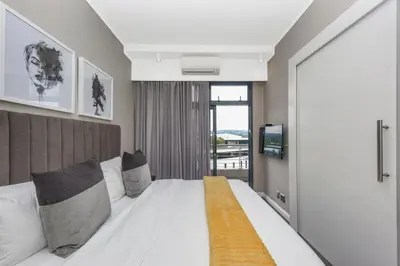a bedroom with a large white bed and a window at Menlyn Main Apartments Trilogy Collection in Pretoria