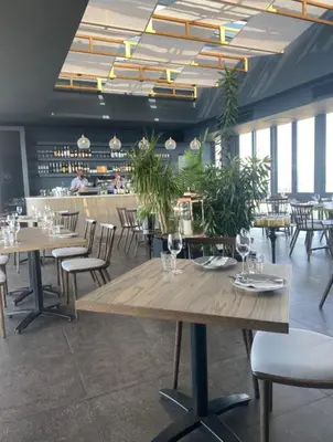 a dining room with tables and chairs and plants at Menlyn Maine Trilogy Apartment 1506 in Pretoria