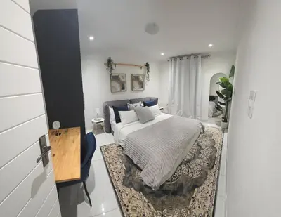 a bedroom with a bed and a table in it at The village Executive Luxe Suites in Thohoyandou
