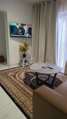 a living room with a table and a tv on the wall at The village Executive Luxe Suites in Thohoyandou