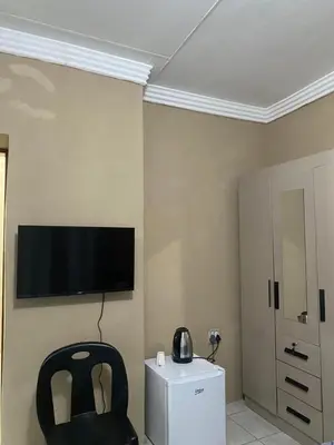 a room with a chair and a television on the wall at Emangwevu Estate in Witbank