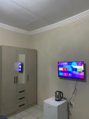 a room with a television on a wall with a refrigerator at Emangwevu Estate in Witbank