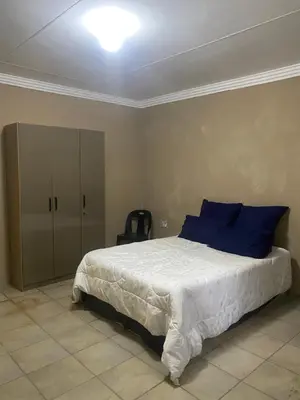 a bedroom with a bed with blue pillows and a cabinet at Emangwevu Estate in Witbank