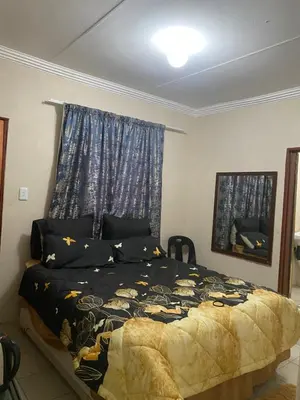 a bedroom with a bed with a blue curtain at Emangwevu Estate in Witbank