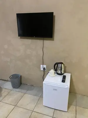 a flat screen tv on a wall with a refrigerator at Emangwevu Estate in Witbank