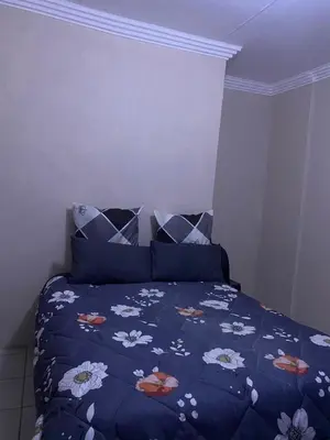 a bedroom with a bed with a blue comforter and pillows at Emangwevu Estate in Witbank