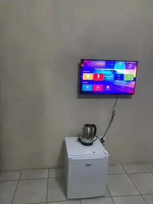 a tv on a wall with a tea kettle on top of a refrigerator at Emangwevu Estate in Witbank