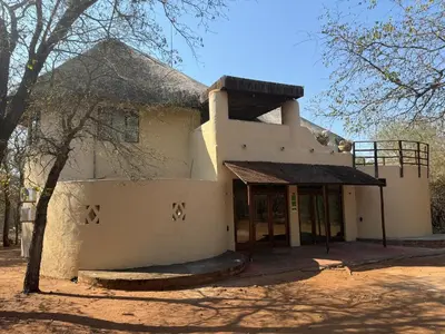 a white building with a tree in front of it at Villa Leopards Lookout in Marloth Park