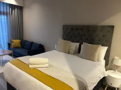 a bedroom with a large bed and a blue couch at Menlyn Maine Trilogy Apartments When Home is Far in Pretoria