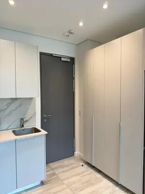 a kitchen with white cabinets and a sink and a door at Menlyn Maine Trilogy Apartments When Home is Far in Pretoria