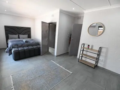 a bedroom with a bed and a mirror and a rug at Soliha Guesthouse in Trichardt